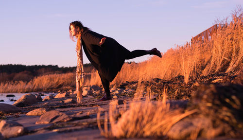 Woman standing at beach against clear sky during winter