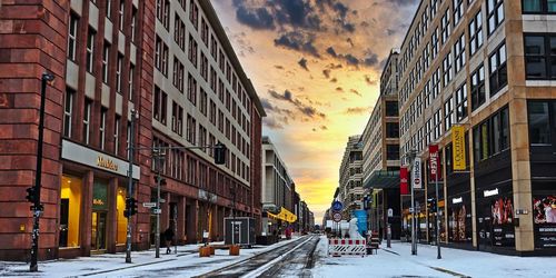 Street amidst buildings against sky during sunset in city