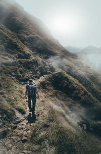 Rear view of backpacker walking on mountain