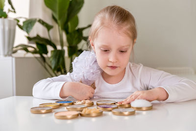 A girl student sits at a desk in the classroom and collects figures / puzzles / small toys 