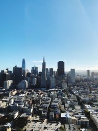 Aerial view of buildings in city against clear blue sky