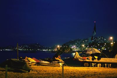 Illuminated beach against clear blue sky at night