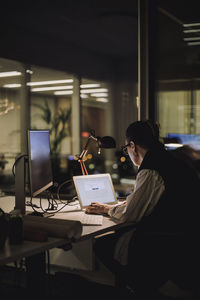 Businesswoman using laptop while working overtime in office at night