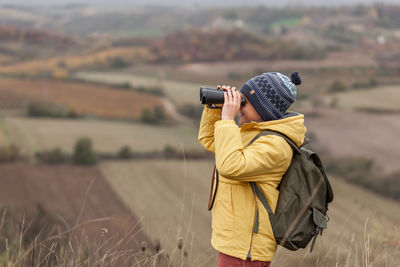 Rear view of person photographing on field