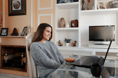 Portrait of woman sitting on table at home