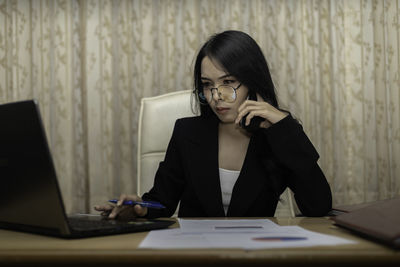 Woman using phone while sitting on table