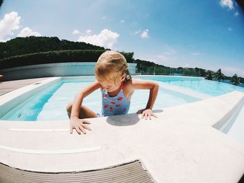 Cute girl in swimming pool against sky