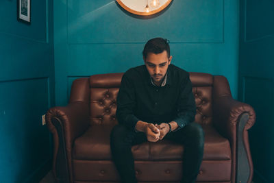 Full length of young man sitting on sofa