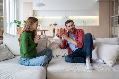 Young woman using digital tablet while sitting on bed at home