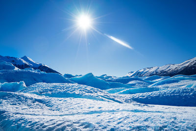 Scenic view of snowcapped mountains against blue sky