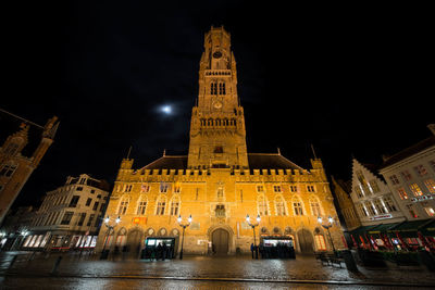 Low angle view of illuminated clock tower at night