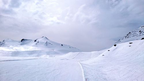 Scenic view of snow covered mountains against cloudy sky