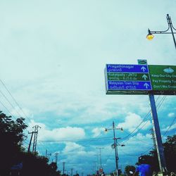 Low angle view of electricity pylon against cloudy sky