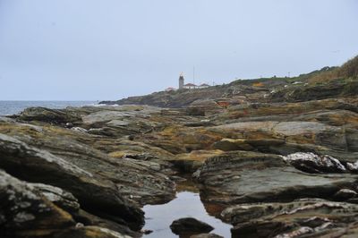 Rocks by sea against clear sky