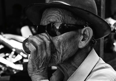 Close-up of senior man having drink while sitting outdoors