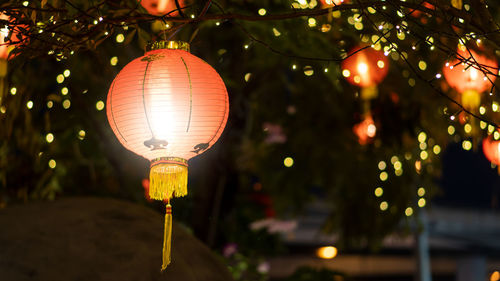 Close-up of illuminated lanterns hanging on street at night