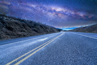 Road by landscape against sky at night