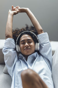Young woman wearing headphones resting on sofa at home