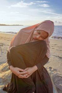 Midsection of woman standing at beach against sky