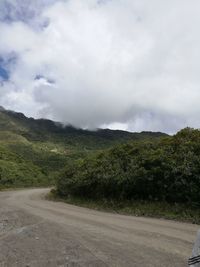 Road passing through landscape against cloudy sky