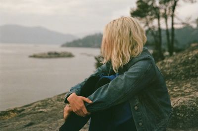 Side view of woman sitting at rock formation