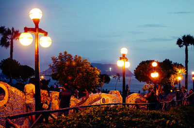 Illuminated street light against sky at dusk