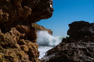 Rock formation by sea against clear sky