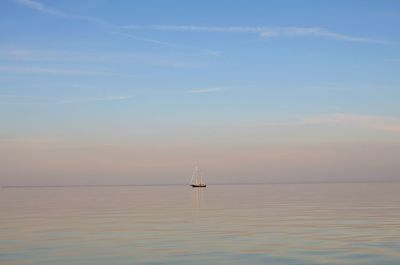 Sailboat sailing on sea against sky during sunset