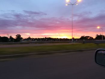 Car on street against sky at sunset