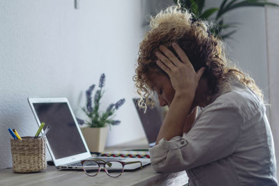 Side view of young woman using mobile phone while sitting at home