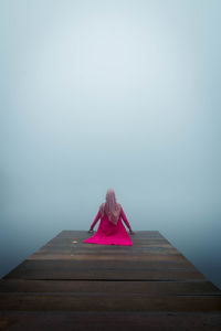 Woman sitting on wooden pier