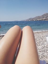 Low section of woman on beach against clear sky