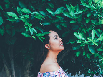 Young woman standing against plants