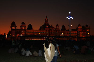 People at illuminated temple against clear sky at night