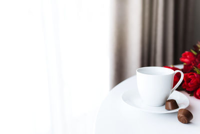 Red tulips bouquete on table, white coffee cup. concept for greeting card for mothers day