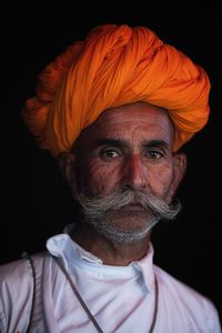 Portrait of man wearing turban against black background