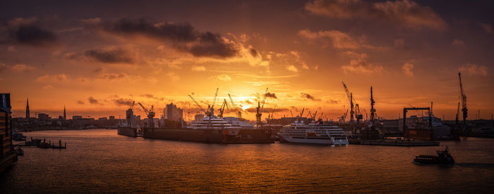 Sailboats moored at harbor during sunset