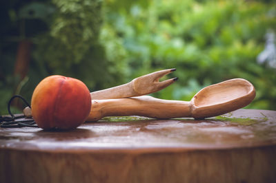 Close-up of wooden spoon and carving fork by peach on wet wood
