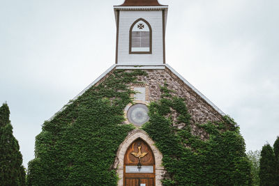 Low angle view of cross on building against sky