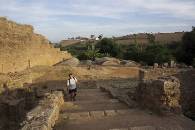 Man on steps at old ruin against sky