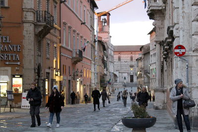 Group of people walking on road along buildings