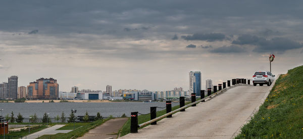 Road by buildings against sky in city