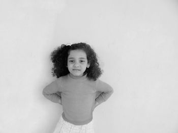 Portrait of cute girl standing against wall