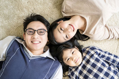 Portrait of smiling family lying down on floor at home