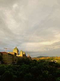 Buildings in city against cloudy sky