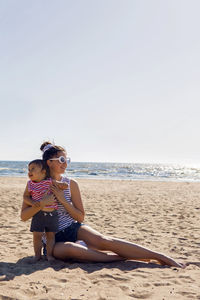 Woman walks with her little son on a sandy beach near the sea in the summer