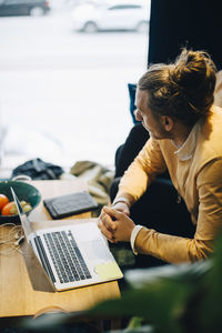 Woman using mobile phone while sitting on table