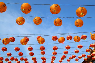 Low angle view of lanterns hanging against orange sky