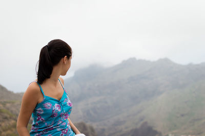 Woman looking at mountains against sky