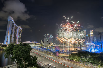 Firework display in city against sky at night